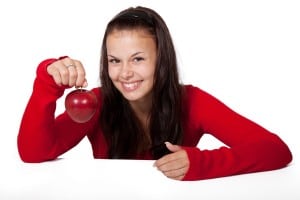 Frau hält roten Apfel und lächelt